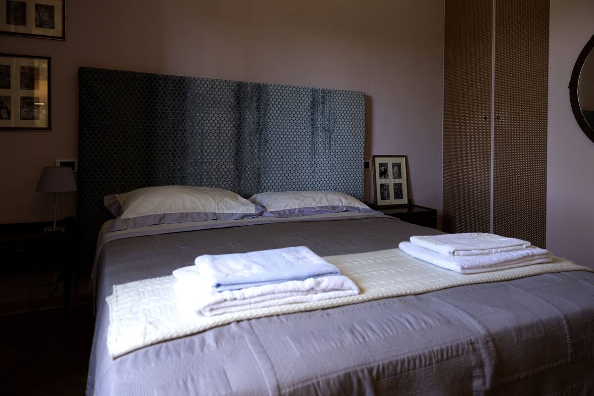 A neatly made bed with a headboard, pillows, and folded towels.