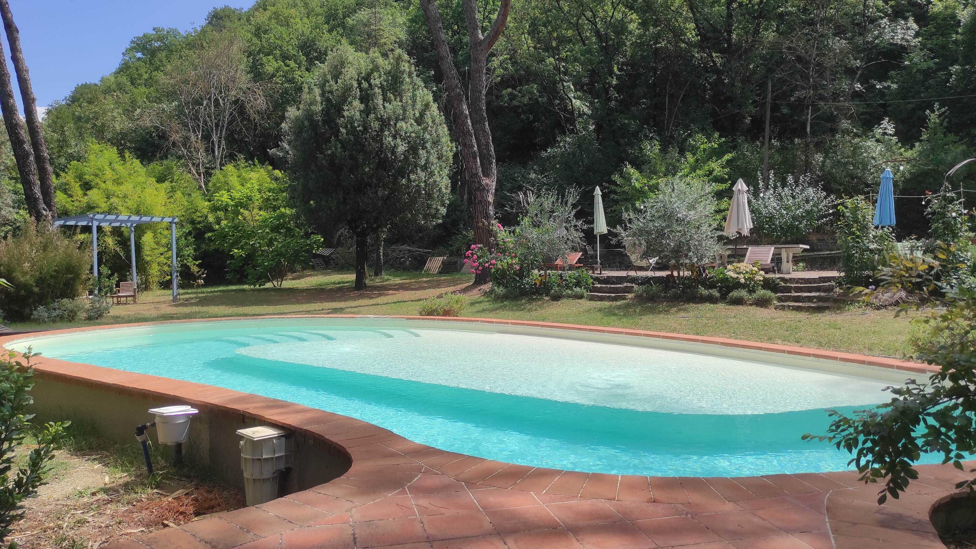 Una piscina con borde de azulejos, rodeada por un patio de ladrillo.