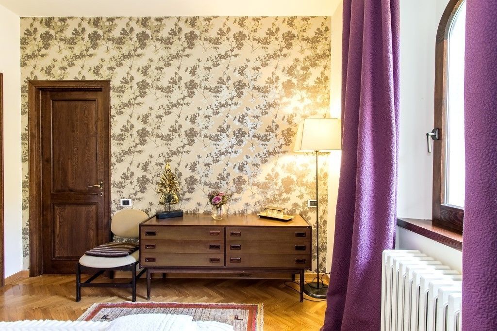 Una habitación con puerta de madera, un aparador, una silla, una lámpara y un radiador.