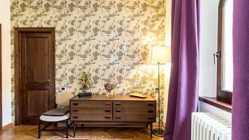 Una habitación con puerta de madera, un aparador, una silla, una lámpara y un radiador.