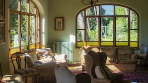 A cozy living room with a large arched window, a chandelier, and comfortable seating.