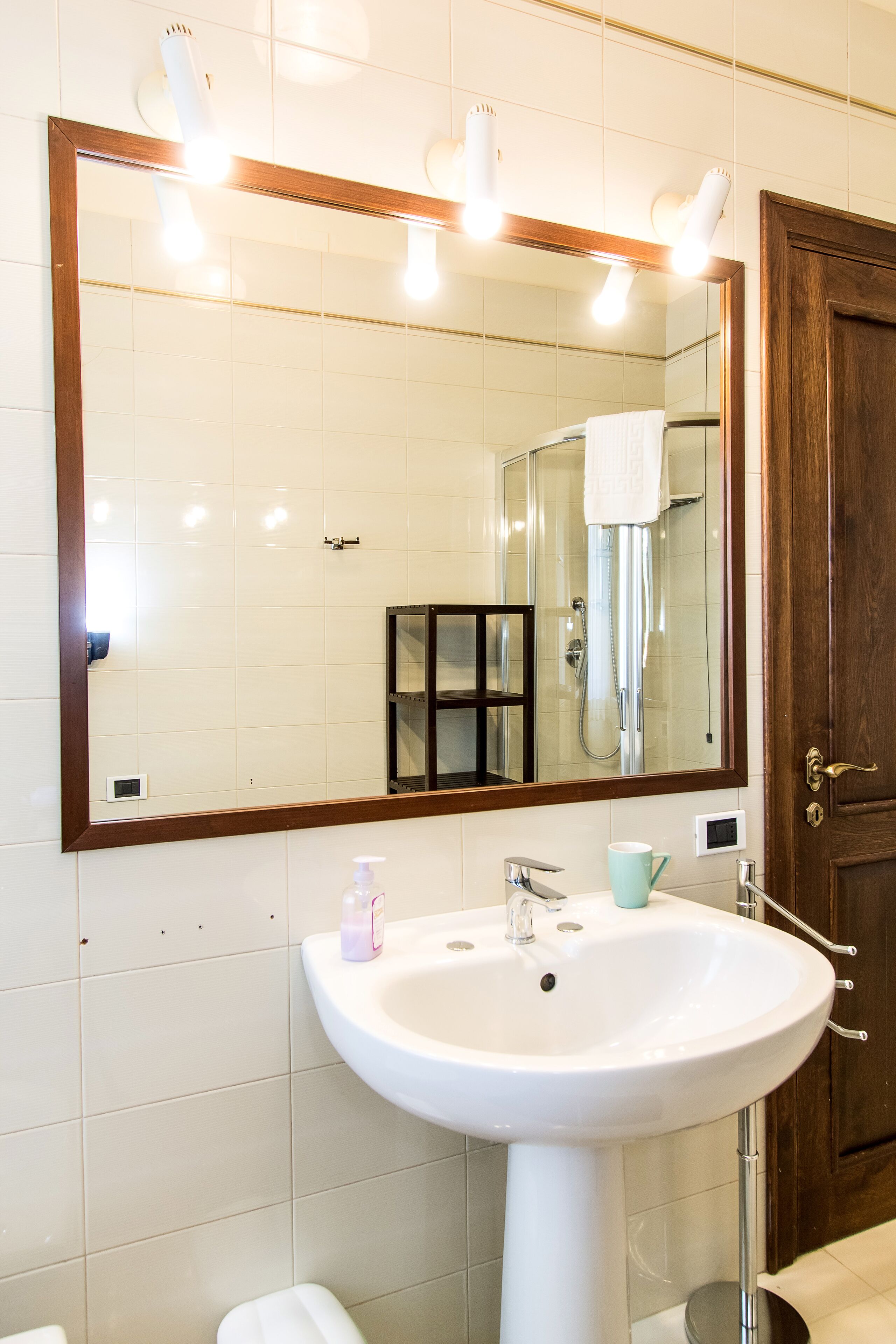 A bathroom with a white sink, a large mirror, and a shower.
