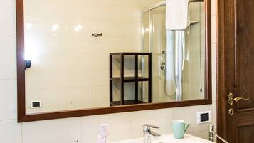 A bathroom with a white sink, a large mirror, and a shower.