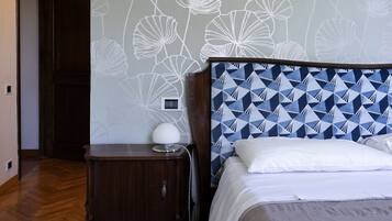 Un dormitorio con pared estampada, cabecero de madera, mesita de noche con lámpara y alfombra estampada.