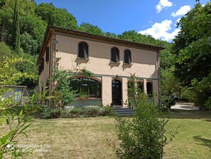 A two-story building with a beige facade, arched windows, and a small porch. - Villa La Ginestra (Subbiano)
