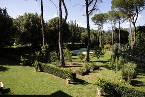 A well-maintained garden with a swimming pool, surrounded by various trees and shrubs. - Villa La Ginestra (Subbiano)