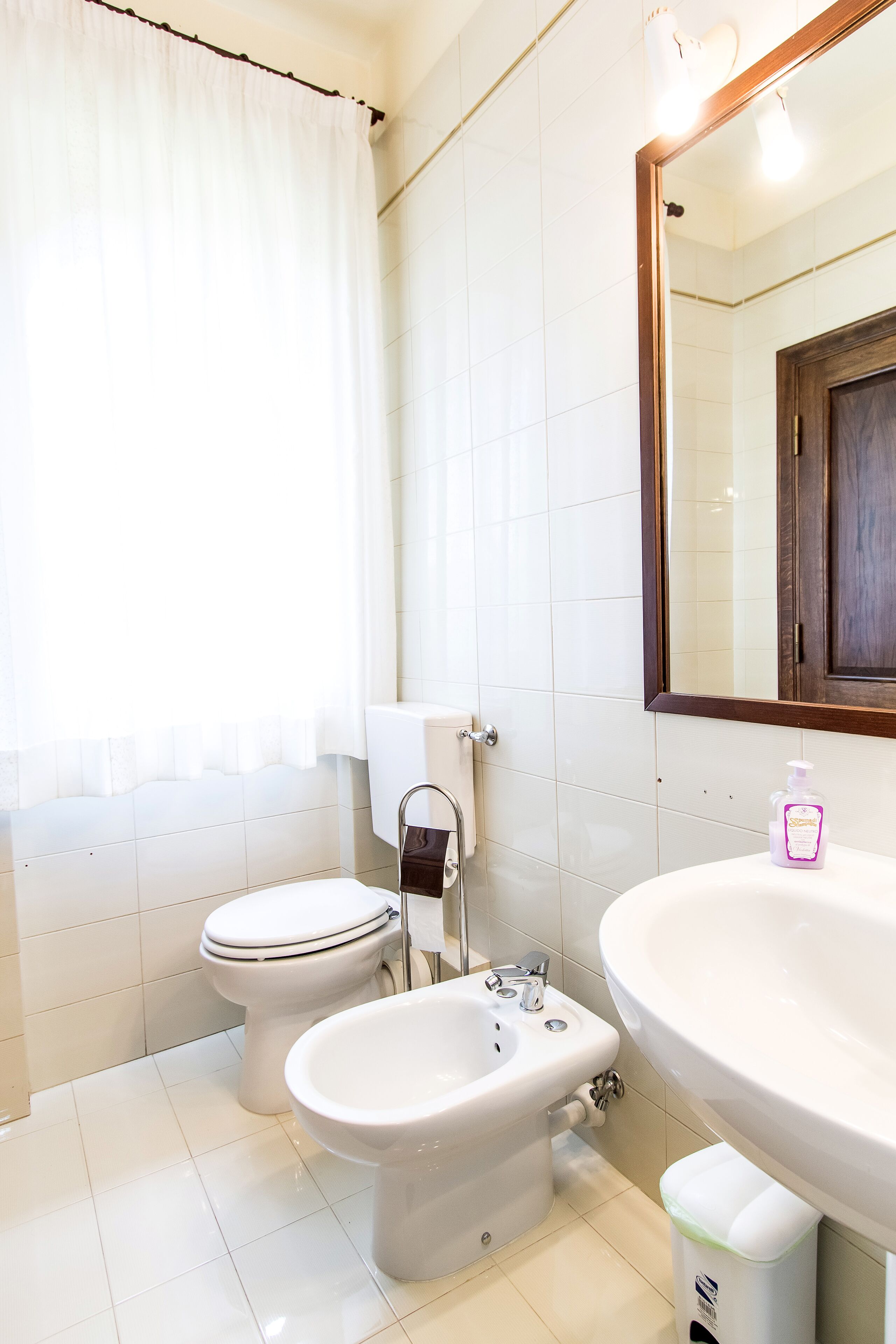 Une salle de bain équipée de toilettes, d’un bidet, d’un lavabo et d’un miroir.