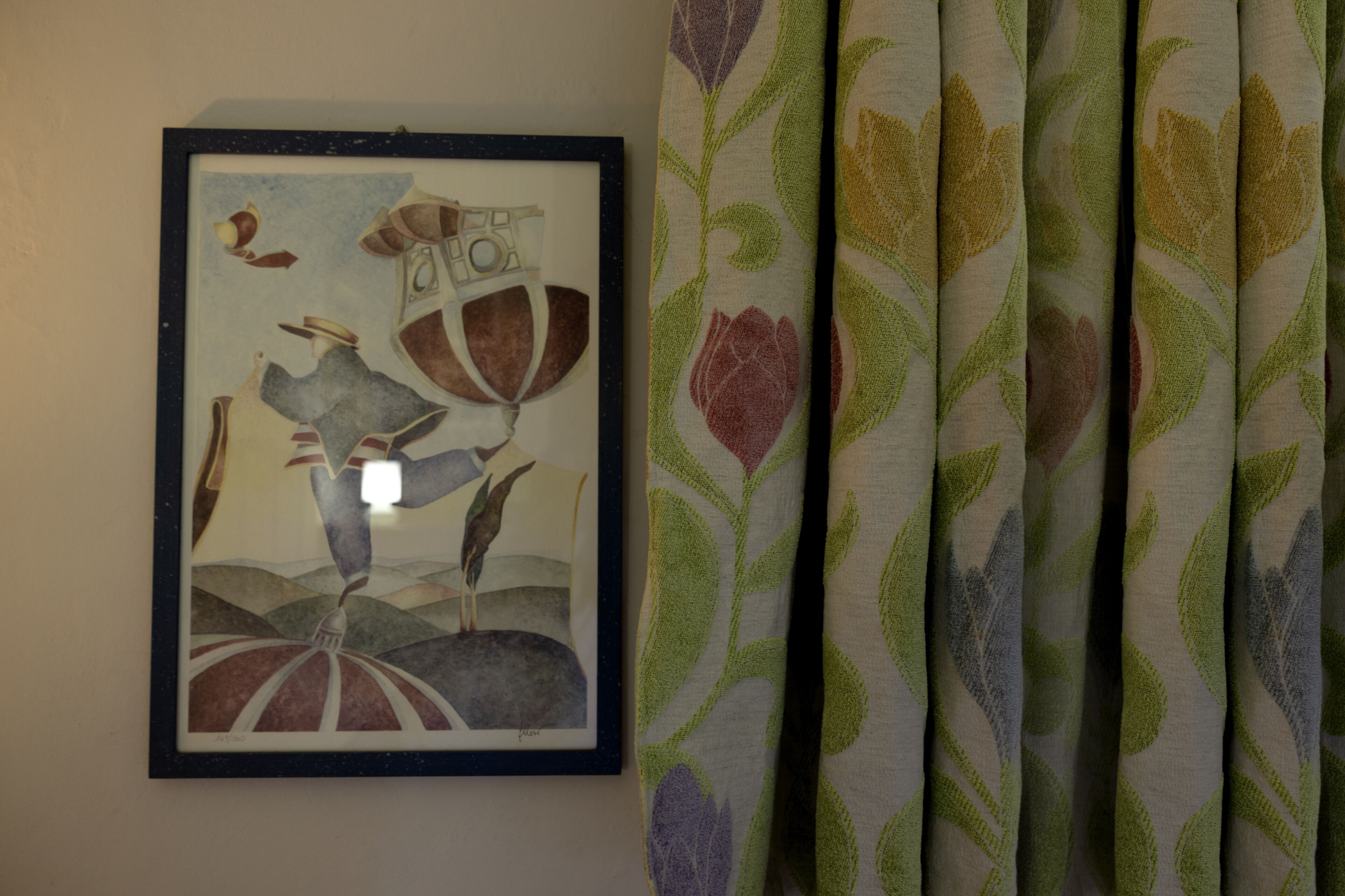 A framed artwork with abstract figures and a patterned curtain.