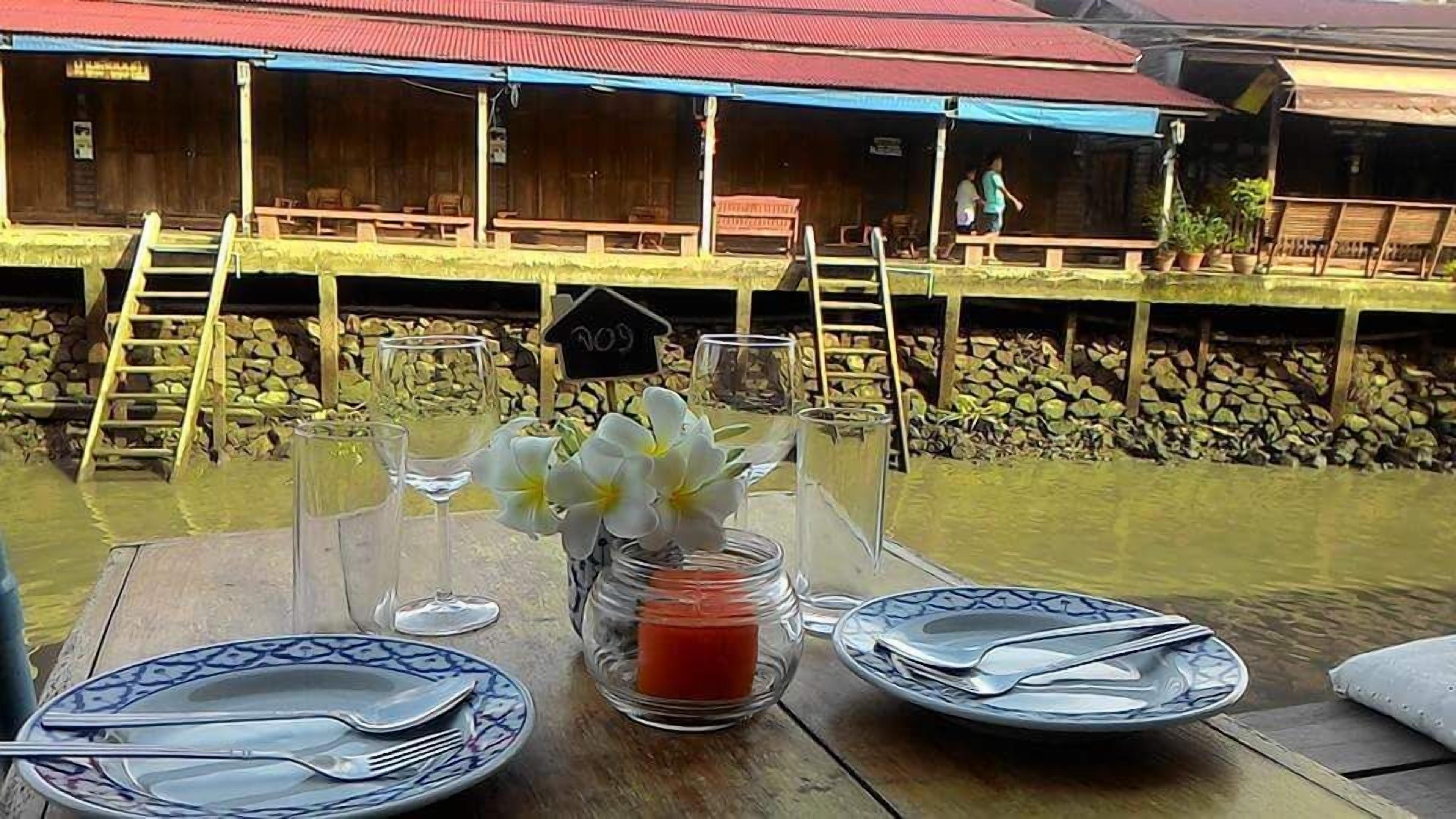 A dining table set with plates, cutlery, and a candle, overlooking a wooden structure with a red roof and a sign reading "2009".