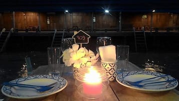 A table set for two with plates, cutlery, glasses, a candle, and a sign indicating a price of 209.