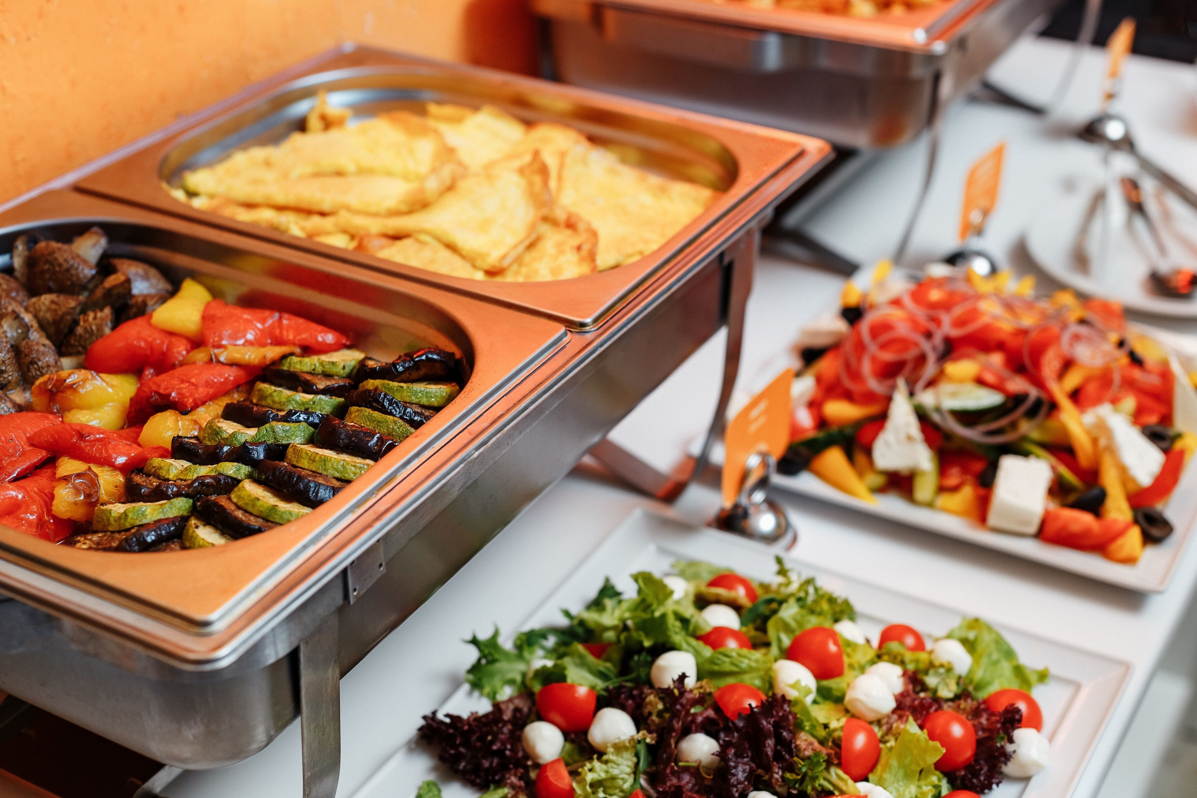 Un bufé con diversos platos, incluyendo verduras asadas, carnes a la parrilla y ensaladas.