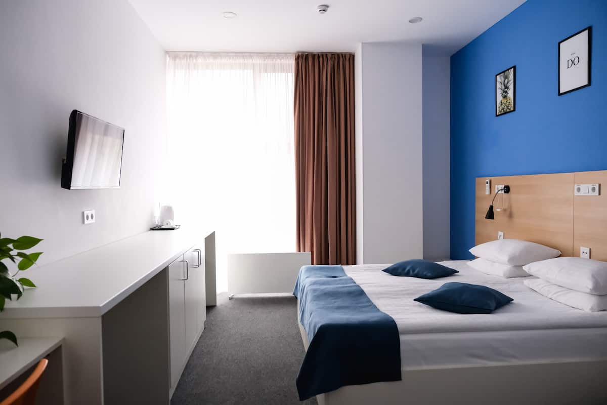 Una habitación de hotel moderna con cama, escritorio y televisión.