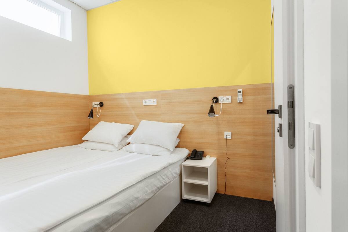 Un dormitorio pequeño y ordenado con cama, mesitas de noche y una puerta.