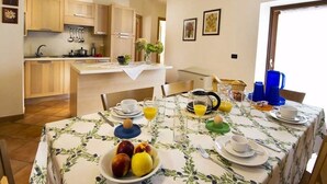 Comedor con una mesa lista para el desayuno, con platos, tazas y un bol de fruta.