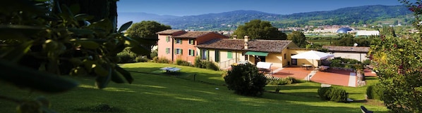 Eine Villa mit Tennisplatz, Sitzgelegenheiten im Freien und Blick auf die umliegende Landschaft.