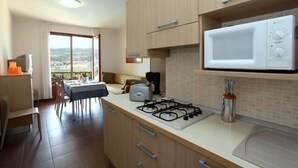Una cocina moderna con estufa a gas, microondas y un comedor con mesa y sillas.