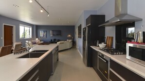 A modern kitchen with a central island, stainless steel appliances, and a dining area with a sofa and chairs. - Lakefront Holiday Home (Okere Falls)