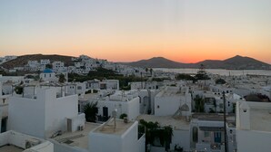 A coastal town with white buildings and blue domed structures, likely a hotel area with flat-roofed buildings and a clear view of the sea.
