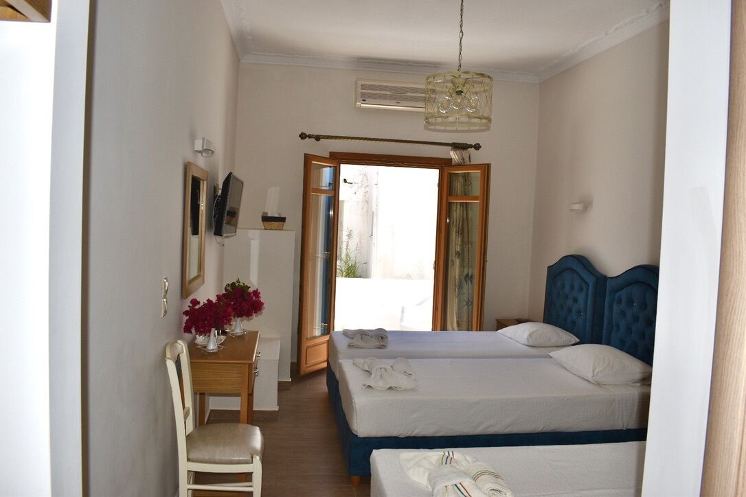A bedroom with two beds, a wooden desk with a chair, a mirror, and a hanging light fixture.