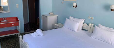 Habitación de hotel con una cama grande, un escritorio rojo, un armario pequeño y una puerta que da a otra habitación.