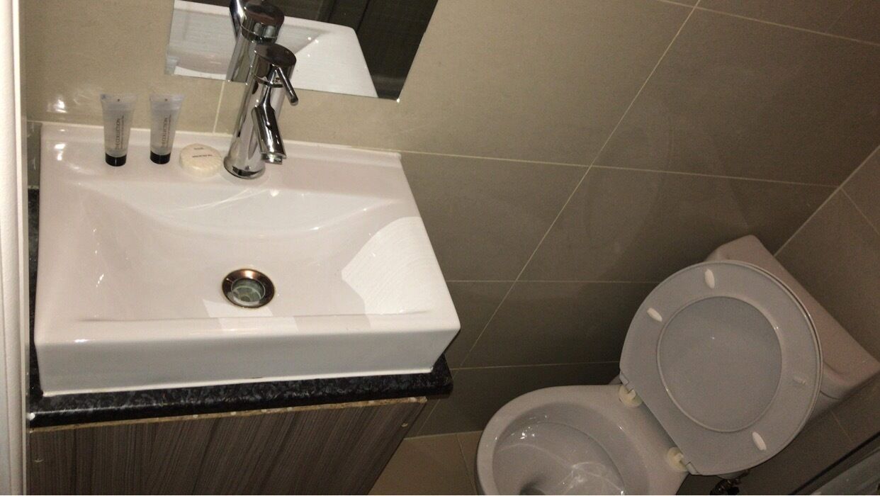 A bathroom with a white sink, a mirror above it, and a toilet.