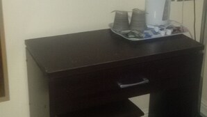 A dark wooden desk with a drawer, a small stool, and a coffee maker on top. - Elsinore Hotel (Llandudno)