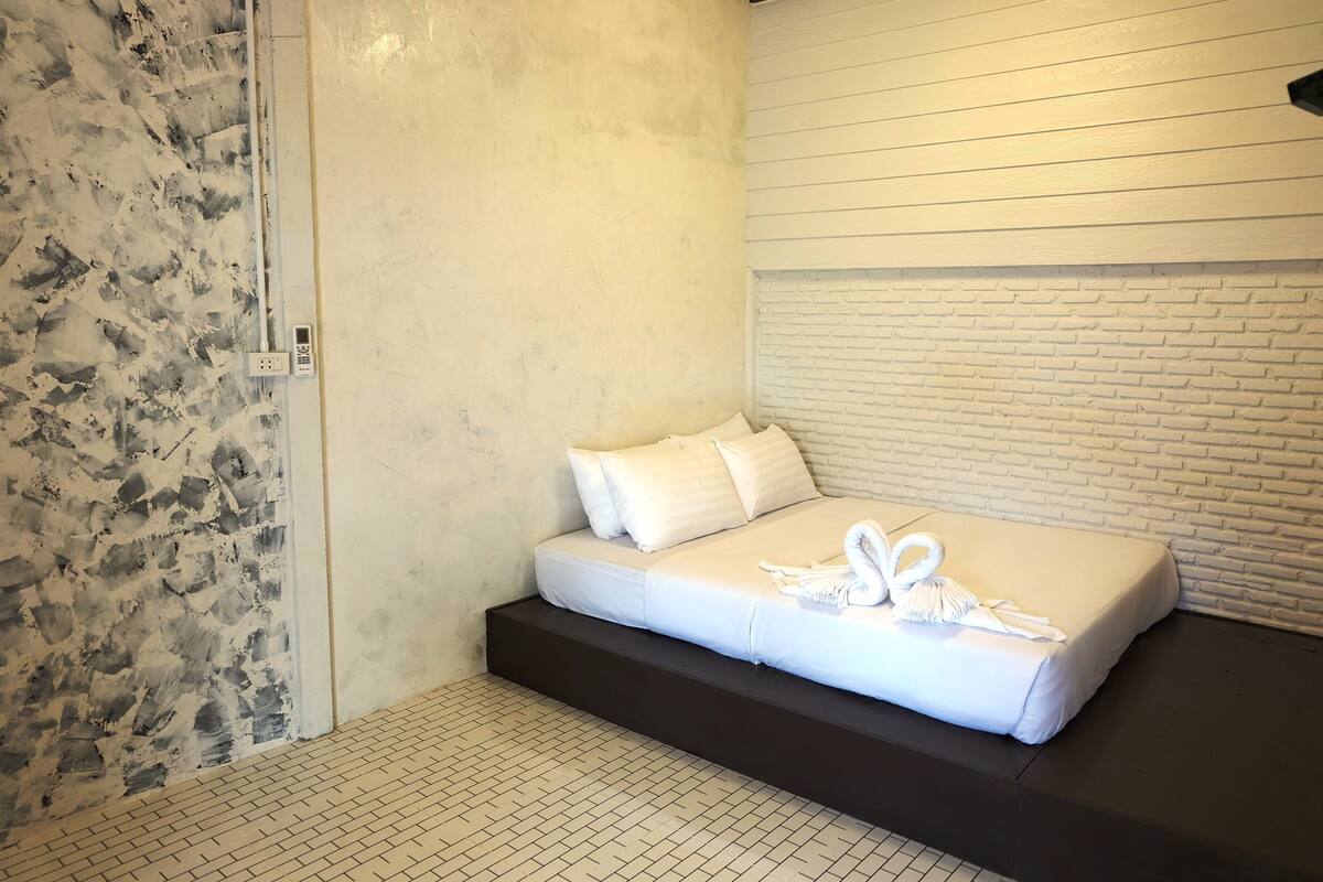 A modern hotel room with a bed, a brick-patterned wall, and a tiled floor.