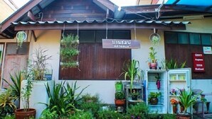 A building with a sign reading "AMINAVA" and a variety of potted plants in front. - BaanChompooAmphawa (Amphawa)