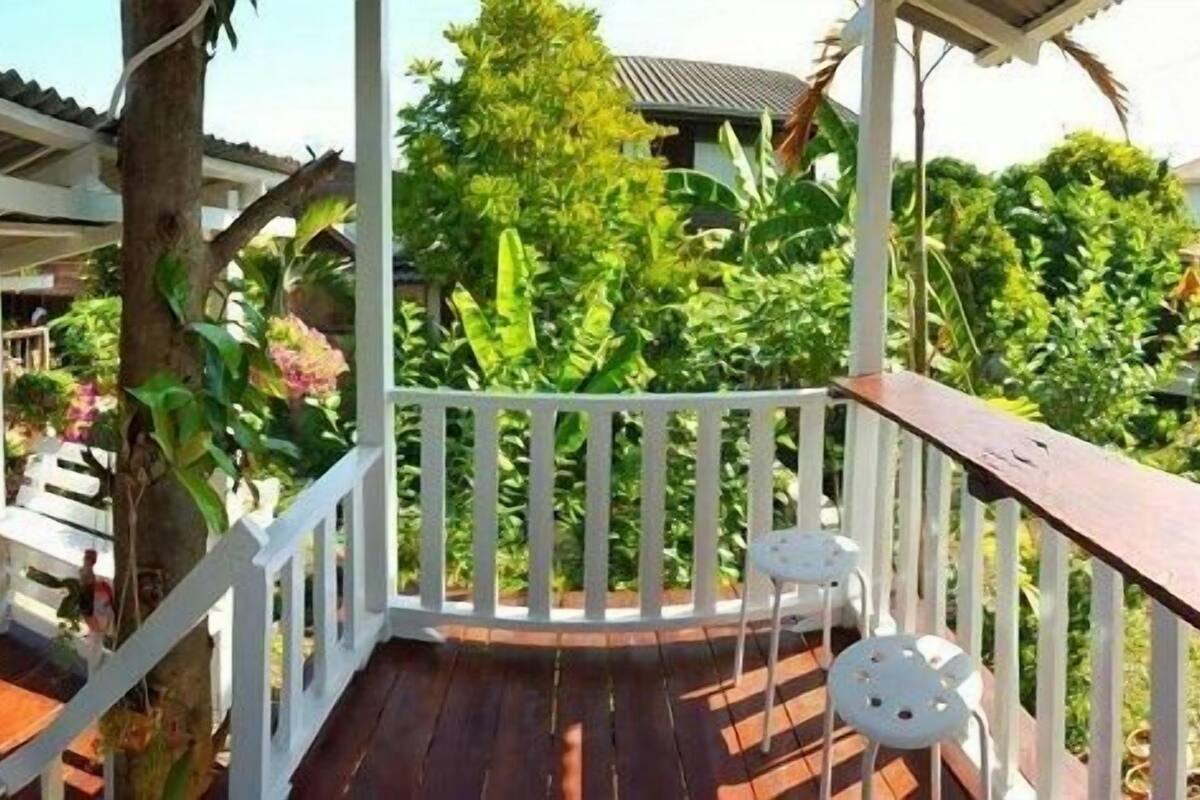 A wooden deck with white railings and two white chairs.