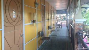 A corridor with yellow walls, metal railings, and chairs along the sides. - Flory's Inn (Liloan)
