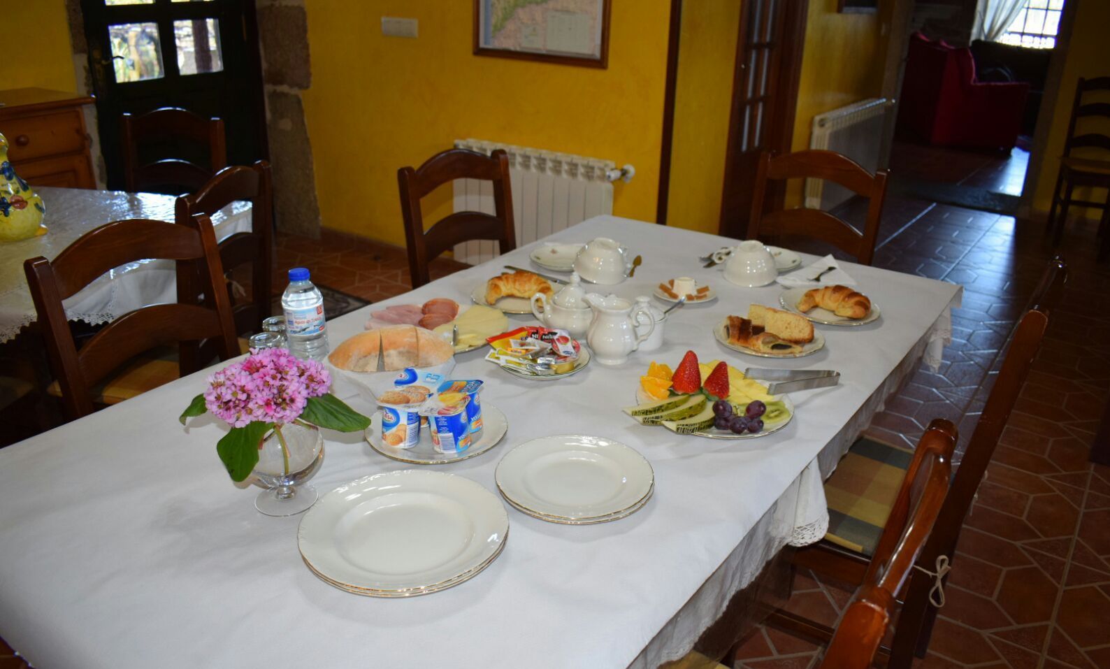 A dining table set with plates, a water bottle, and various food items.