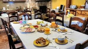 A breakfast table set with various dishes, including croissants, fruit, and orange juice. - Casa Rural Os Carballos (Barro)