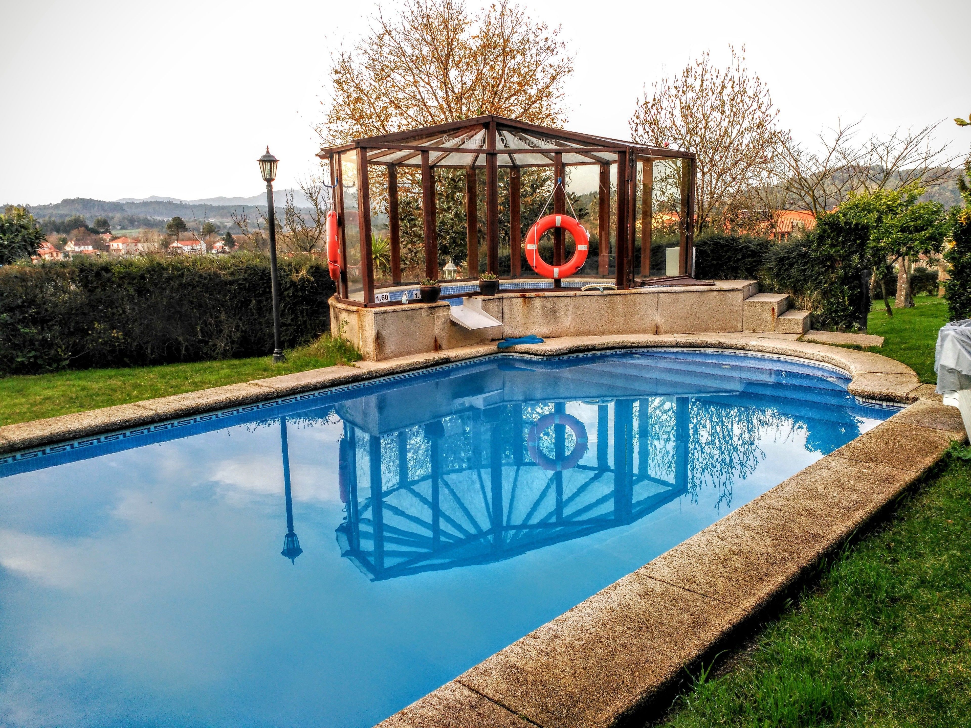 Een buitenzwembad, een zwembad met een waterval en ligstoelen