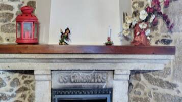 A stone fireplace with a decorative inscription, red lanterns, and a floral arrangement.