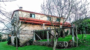 A stone house with a red-tiled roof, a stone staircase, and a grassy yard. - Casa Rural Os Carballos (Barro)