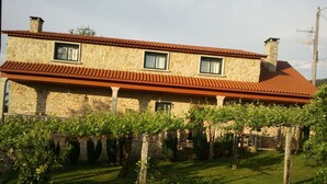 A stone building with a red-tiled roof and two windows. - Casa Rural Os Carballos (Barro)