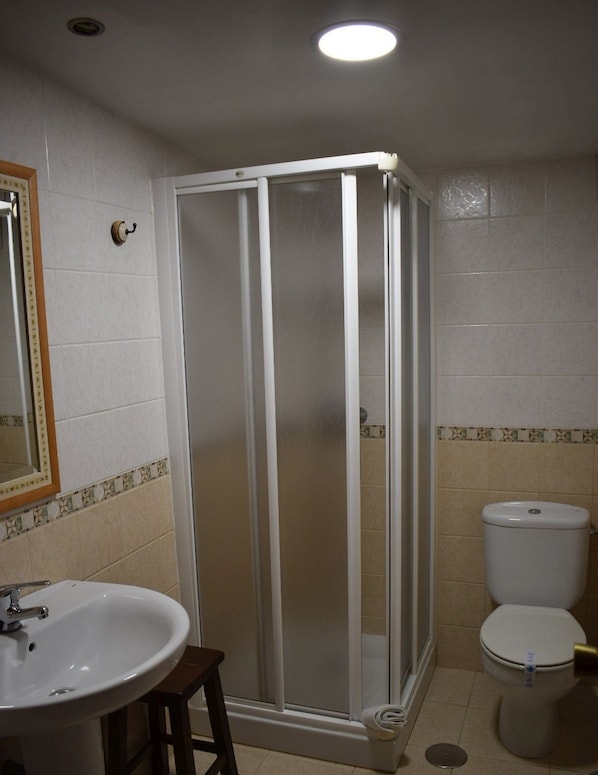 A bathroom with a shower enclosure, toilet, sink, and mirror. - Casa Rural Os Carballos (Barro)
