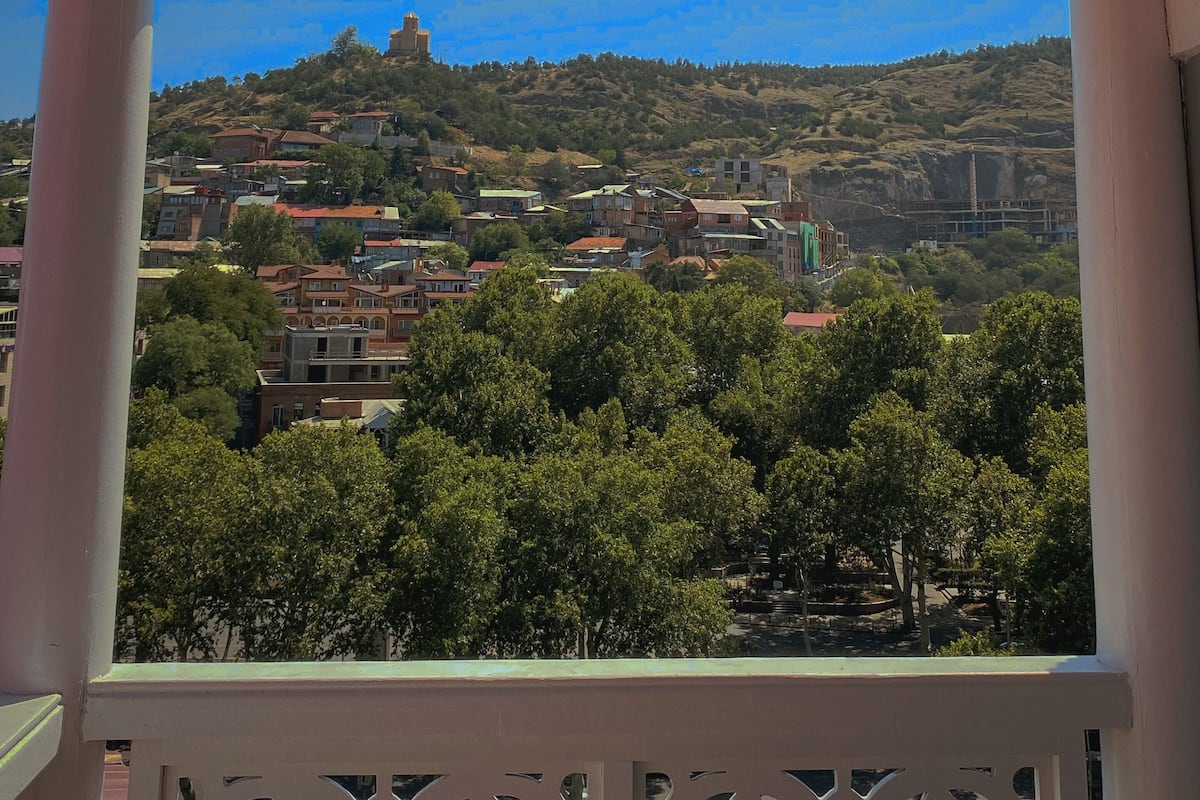 A balcony with a view of a town, including buildings and trees.