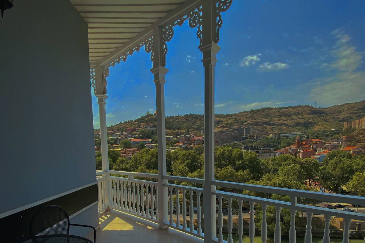 A balcony with white balustrades, two metal chairs, and a table.