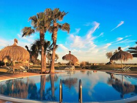 Una piscina cubierta, una piscina al aire libre, sombrillas, tumbonas