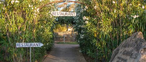Um arco com uma placa que diz "RESTAURANT" leva a um caminho.