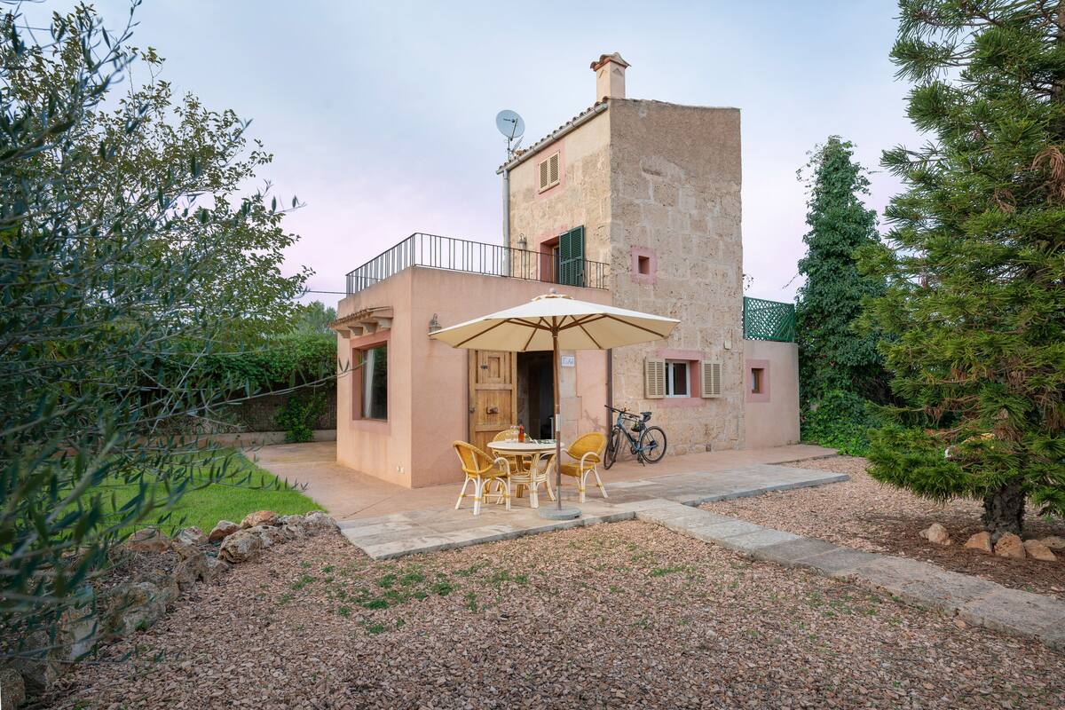 A two-story building with a balcony, a table with chairs, and a bicycle parked outside.