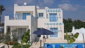 A two-story building with balconies, a pool, and potted plants. - Philippos Villas (Chlorakas)