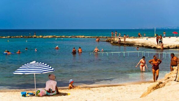 A beach scene with people swimming and sunbathing. - Philippos Villas (Chlorakas)
