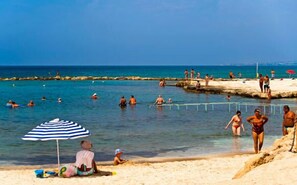 A beach scene with people swimming and sunbathing.