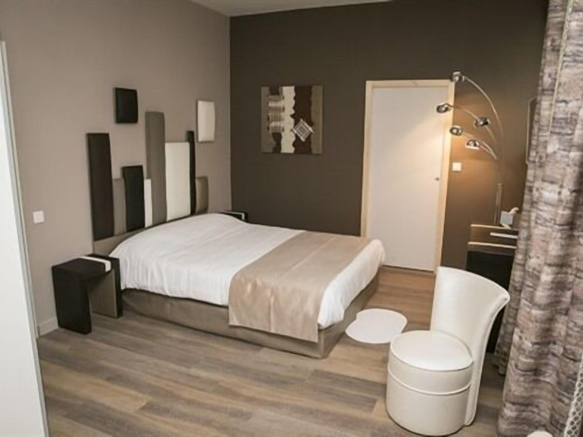 A modern bedroom with a large bed, a bedside table, a chair, and a small round table.