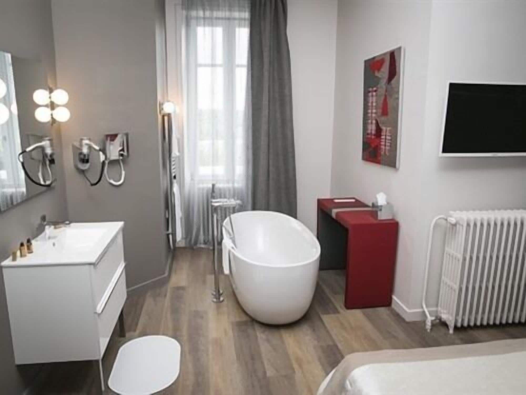 Et moderne badeværelse med et stort badekar, et vaskeskrin med spejl og en radiator.