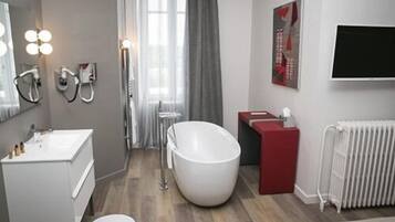 A modern bathroom with a large bathtub, a vanity with a mirror, and a radiator.