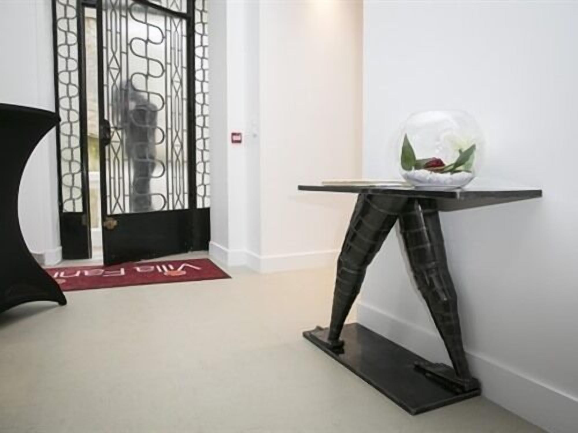 A modern interior with a unique black metal table and a glass bowl with green leaves.