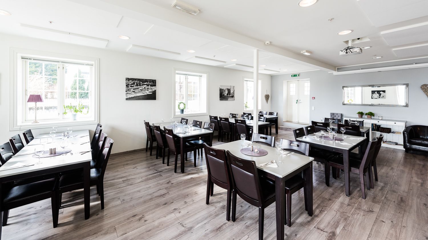 A spacious dining area with multiple tables and chairs, large windows, and a clean, modern design.
